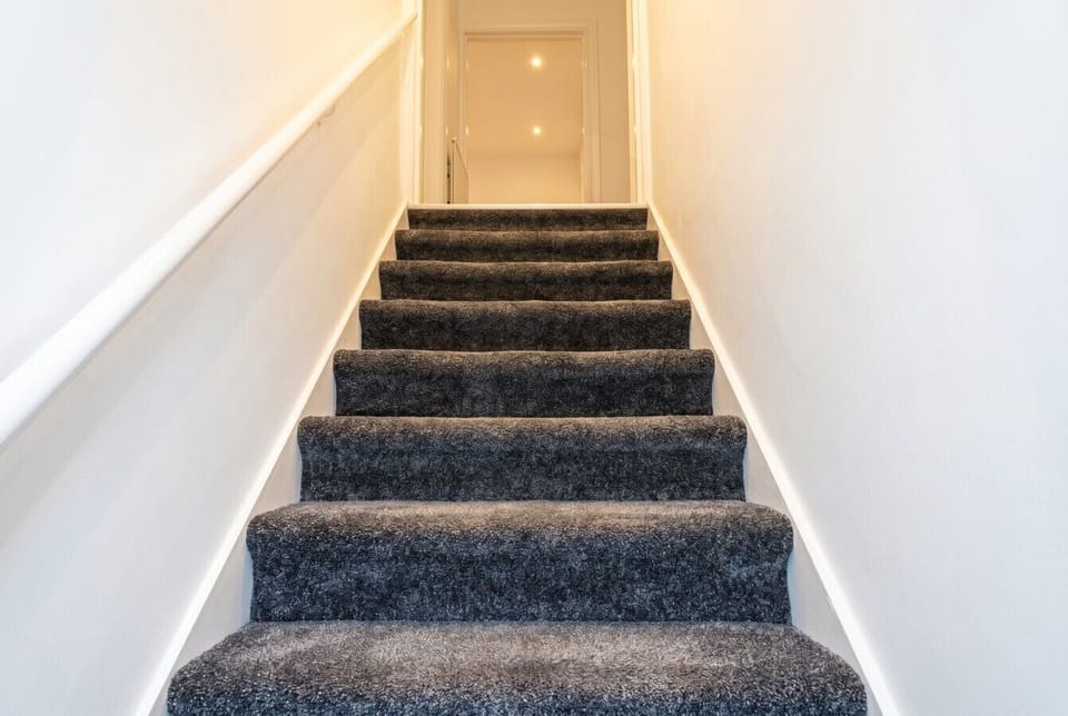 Carpeted staircase leading up to the bedrooms, clean and well-lit for a welcoming arrival.