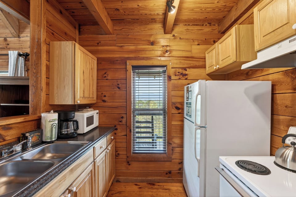 Cozy wood‑planked cabin kitchen with warm lighting, simple essentials, and a rustic charm that feels instantly welcoming.