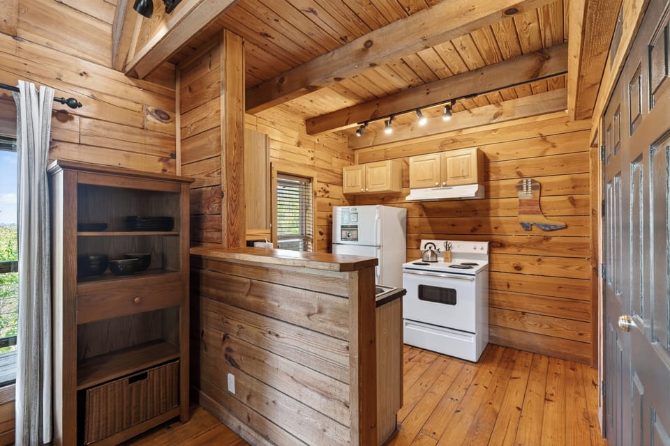 Cozy wood‑planked cabin kitchen with warm lighting, simple essentials, and a rustic charm that feels instantly welcoming.