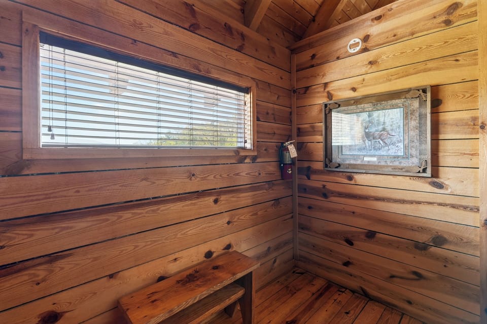 Cozy cabin corner with warm wood walls, nature peeking through the window, and simple rustic charm.