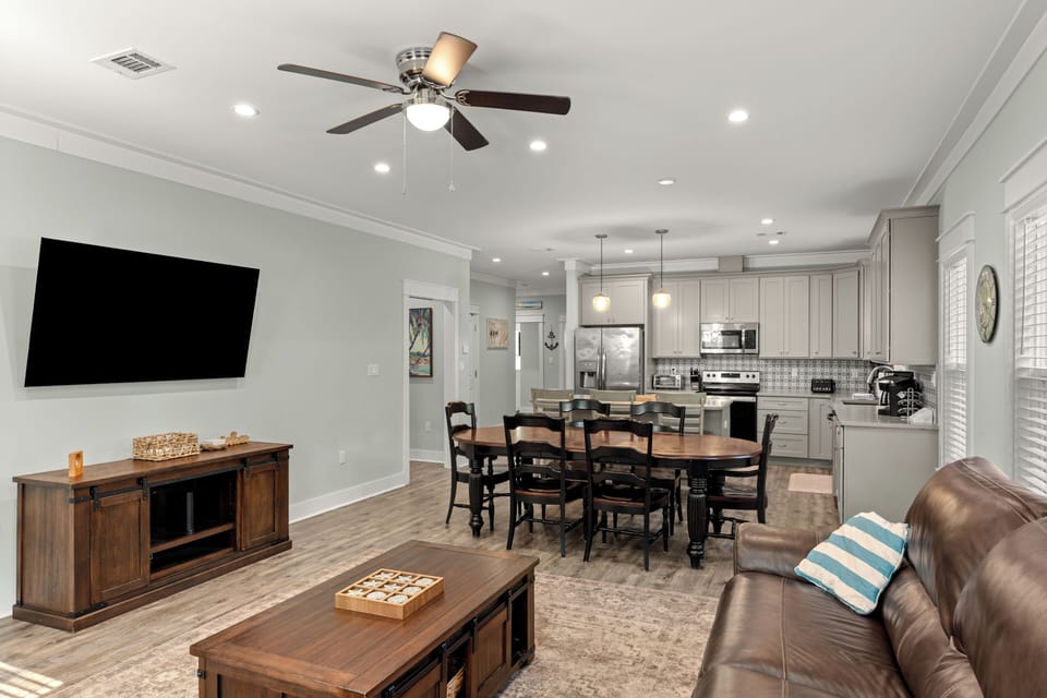 Open-concept living, dining, and kitchen area with ample seating and a wall-mounted TV for easy group gatherings.