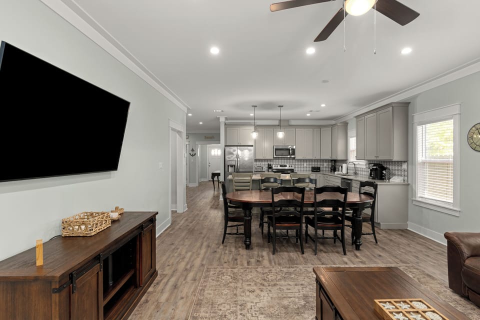 Open-concept living, dining, and kitchen area with ample seating and a wall-mounted TV for easy group gatherings.