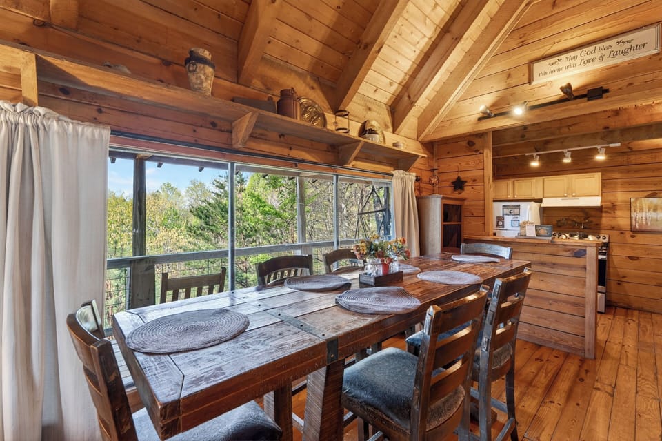 Rustic cabin dining room with warm wood tones, mountain views, and a cozy table set for gathering.