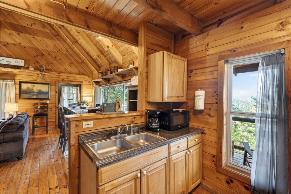 Warm wood‑paneled cabin kitchen with simple comforts, soft lighting, and a cozy rustic charm.