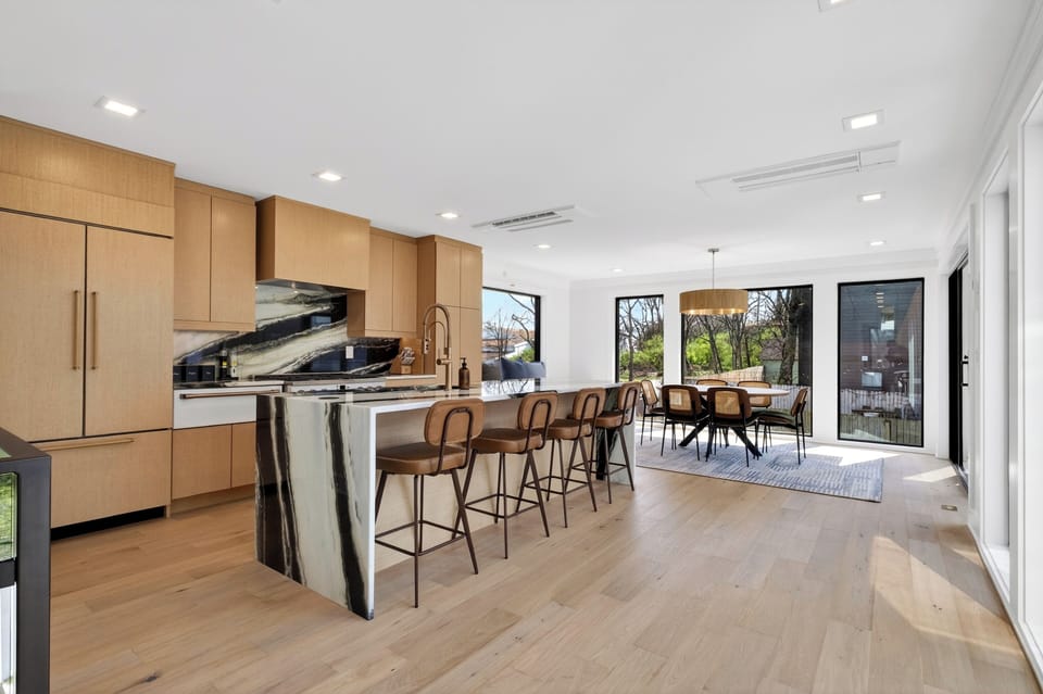 Warm wood tones and bold marble details define this open, design‑forward kitchen and dining area.