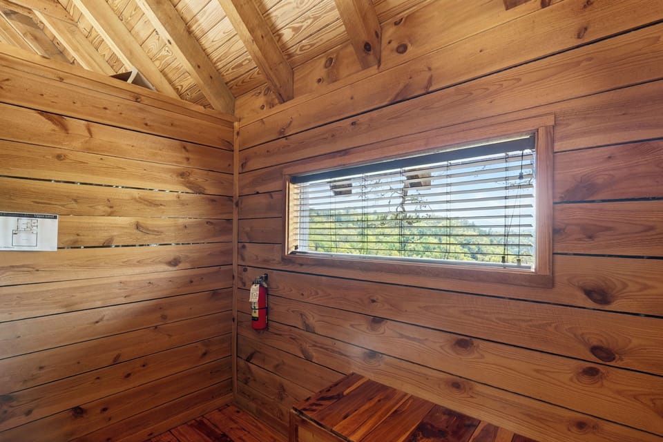 Cozy cabin corner with warm wood walls, nature peeking through the window, and simple rustic charm.