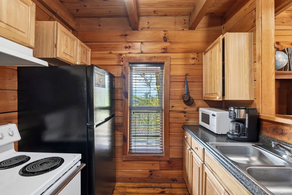 Rustic cabin kitchen with warm wood walls, a cozy breakfast bar, and soft natural light from the window.