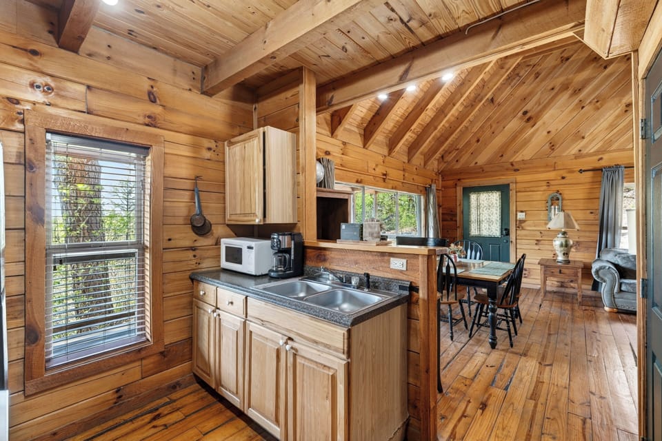 Rustic cabin kitchen with warm wood walls, a cozy breakfast bar, and soft natural light from the window.