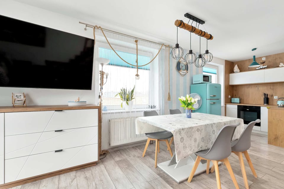 A modern dining area connected to the kitchen, featuring a table with chairs and stylish lighting fixtures.