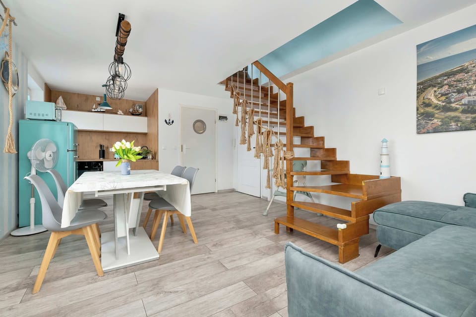 A wider shot of the living room and dining area with pastel accents and a welcoming layout.