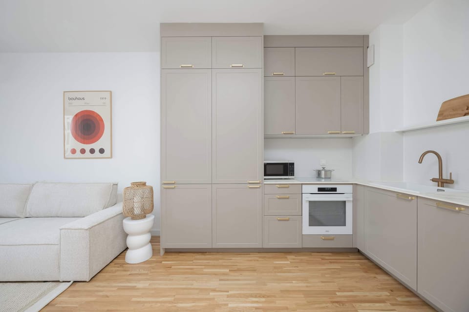 Minimalist kitchenette with light cabinetry, built-in appliances, and clean countertops.