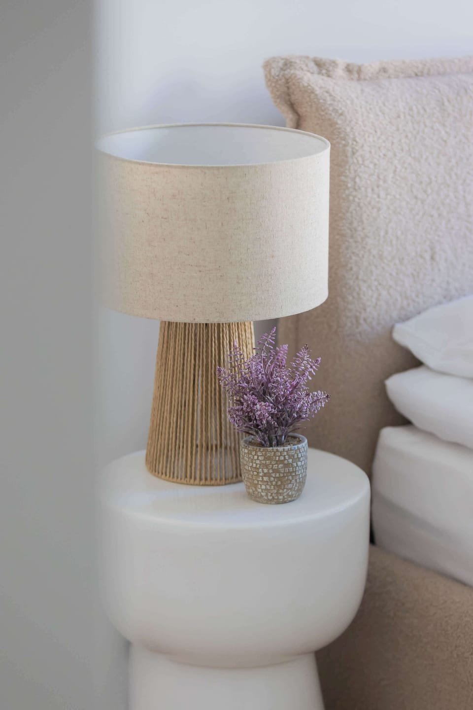 Bedside table with a lamp, flowers, and cozy details.