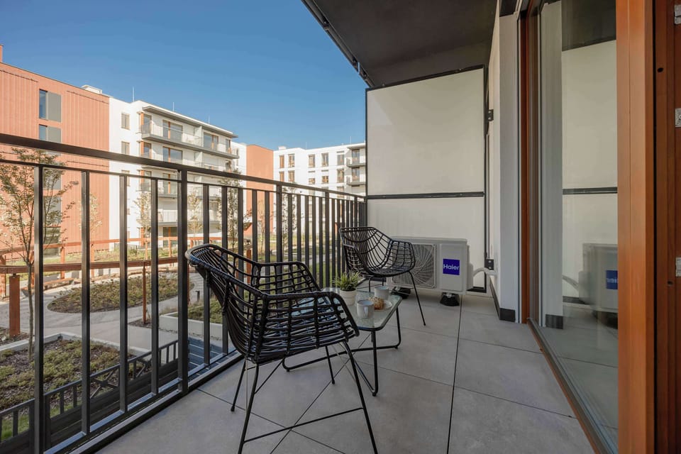 Balcony with outdoor seating overlooking a residential courtyard.