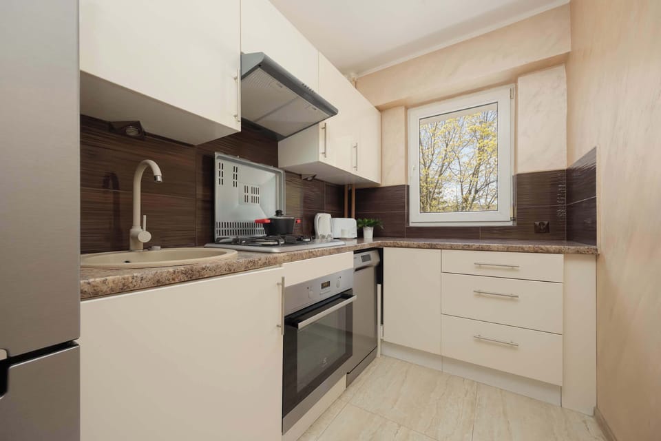 The kitchen layout is functional and bright, featuring white cabinets and a window that provides ventilation. It is fully equipped with an oven and integrated stovetop.