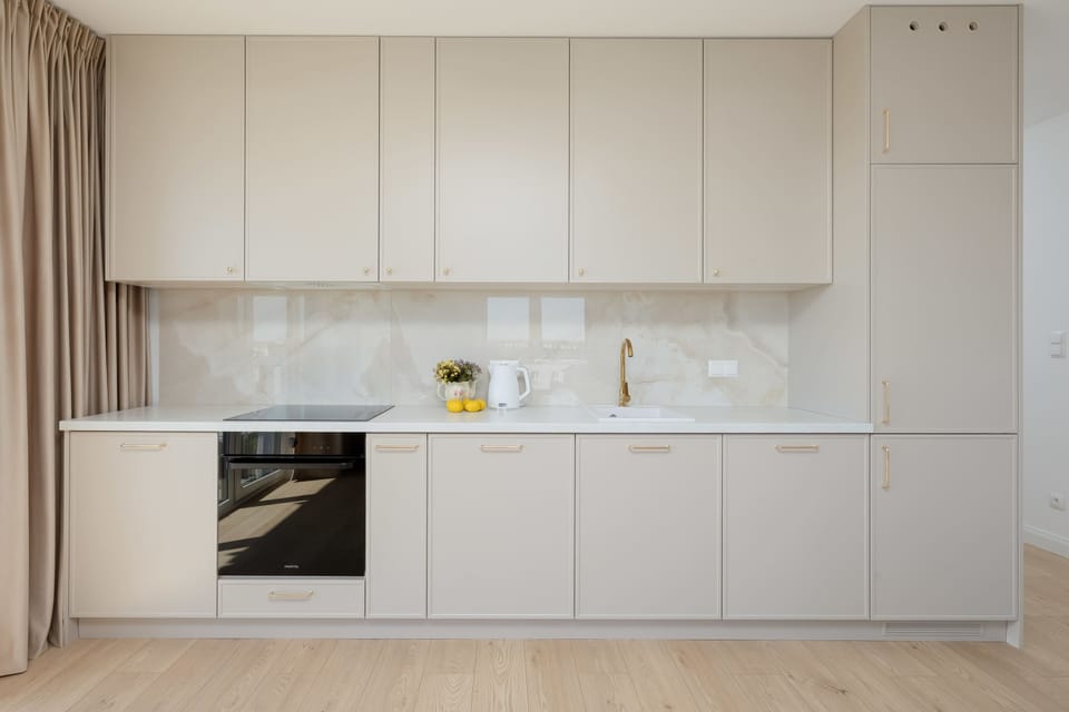 The sleek kitchenette is designed with handleless white cabinetry and integrated appliances for a seamless look. High-quality finishes and under-cabinet lighting emphasize the premium standard of the interior.