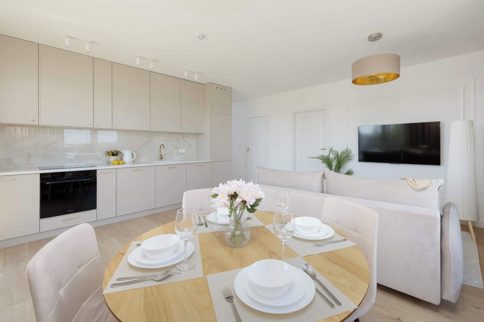 The dining table is beautifully set with white porcelain and glassware, ready for a shared meal. A vase with fresh flowers serves as a charming centerpiece in the heart of the home.