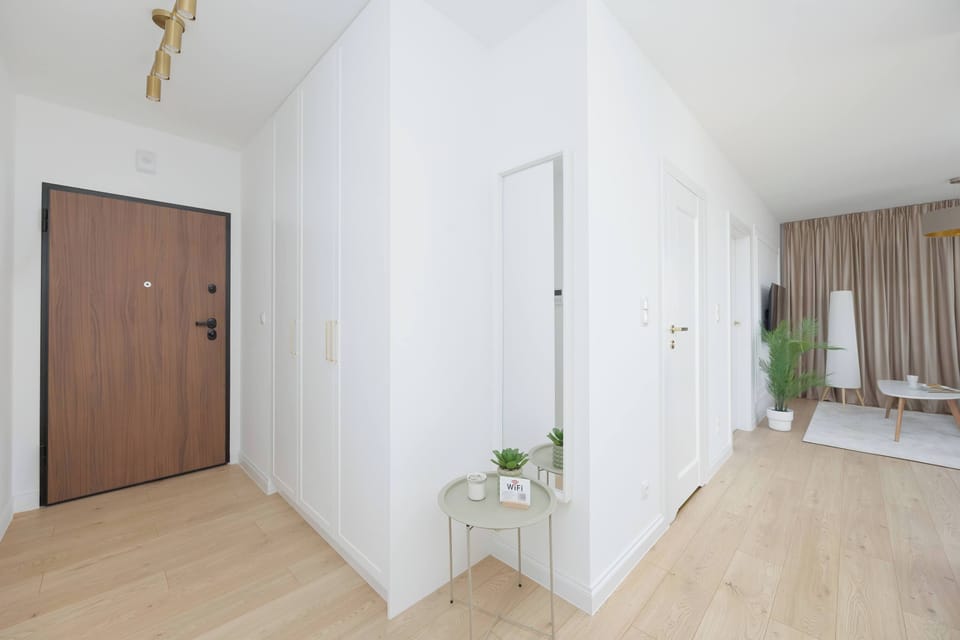 The entrance area is equipped with a large mirror and a small console table, providing a convenient spot for keys and personal items. A solid wooden door ensures security and privacy for the occupants.