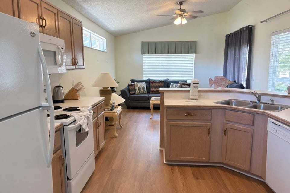 Spacious kitchen featuring wooden cabinetry, full appliances, and a large breakfast bar. Plenty of counter space for preparing meals at home.