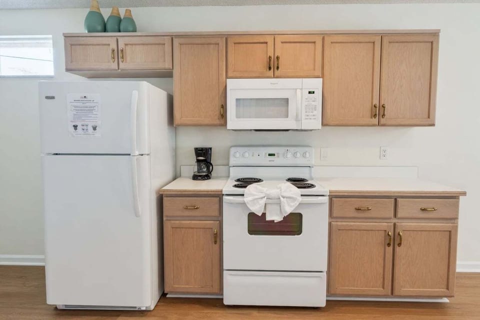 Modern kitchen with full-size refrigerator, stove, microwave, and ample wooden cabinetry. Everything you need to prepare home-cooked meals during your stay.