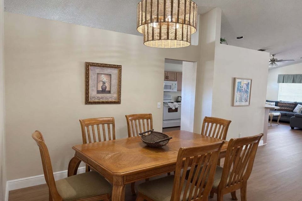 Beautiful dining space with a large wooden table and seating for 6. The warm chandelier and open layout make it ideal for family meals and game nights.