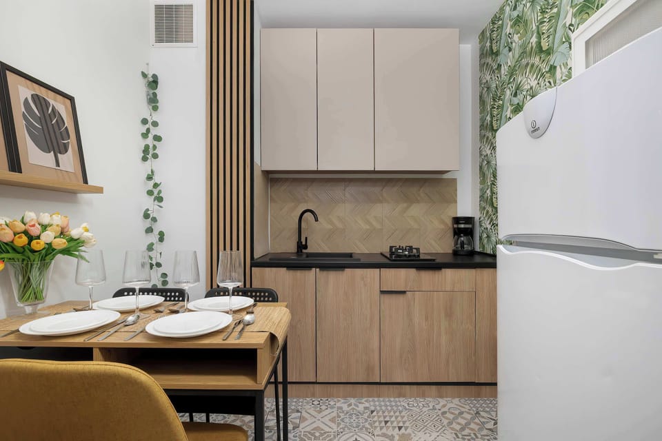 A compact kitchen and dining area with wooden cabinets, a small table set for meals, and warm decorative accents.