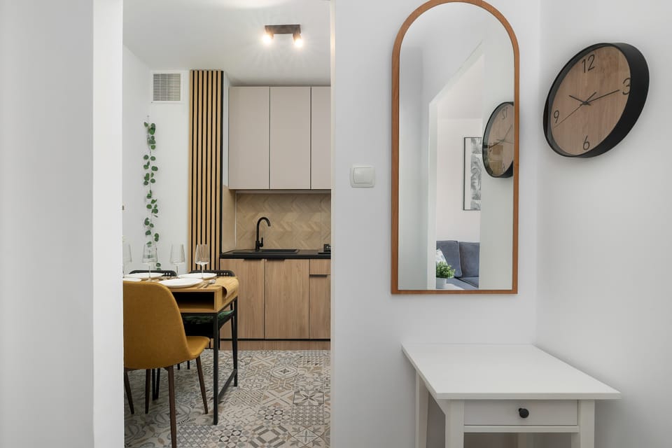 A hallway with a mirror, a small console table, and a glimpse into the kitchen area.