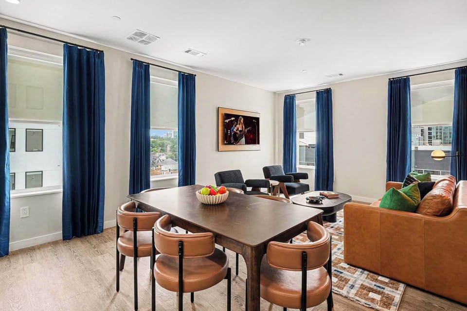 Open concept living area with designer furnishings, smart TV, and direct access to dining area and kitchen