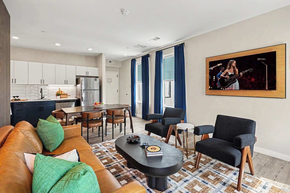 Bright and open living area featuring a smart TV and plush furnishings. Connects to the dining area and kitchen.