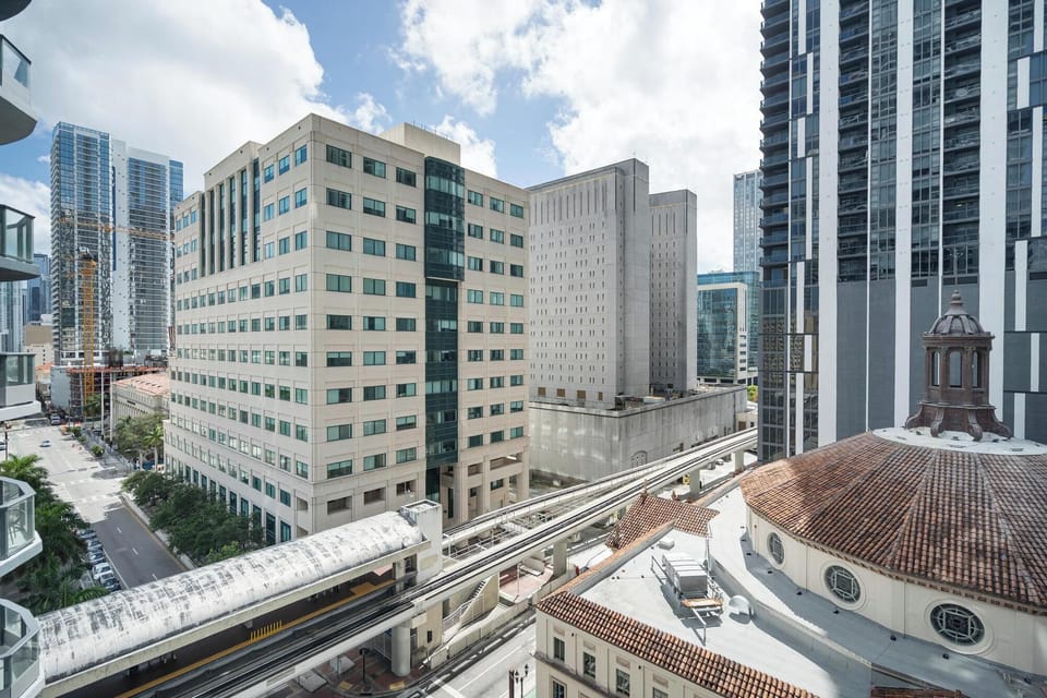 View of downtown city buildings and a nearby metro rail track from the balcony.