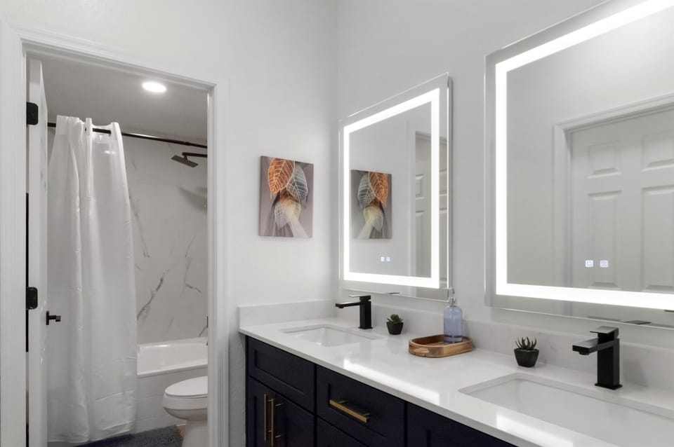 Modern bathroom featuring a spacious vanity, illuminated mirror, and a shower with a tub combination. (Use "walk-in shower" instead if there's no tub.)