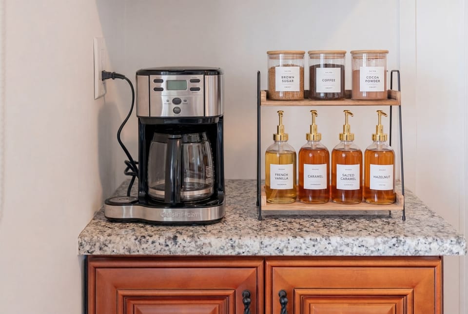 Coffee station stocked w/ flavored syrups & sugar, ready for your morning brew.
