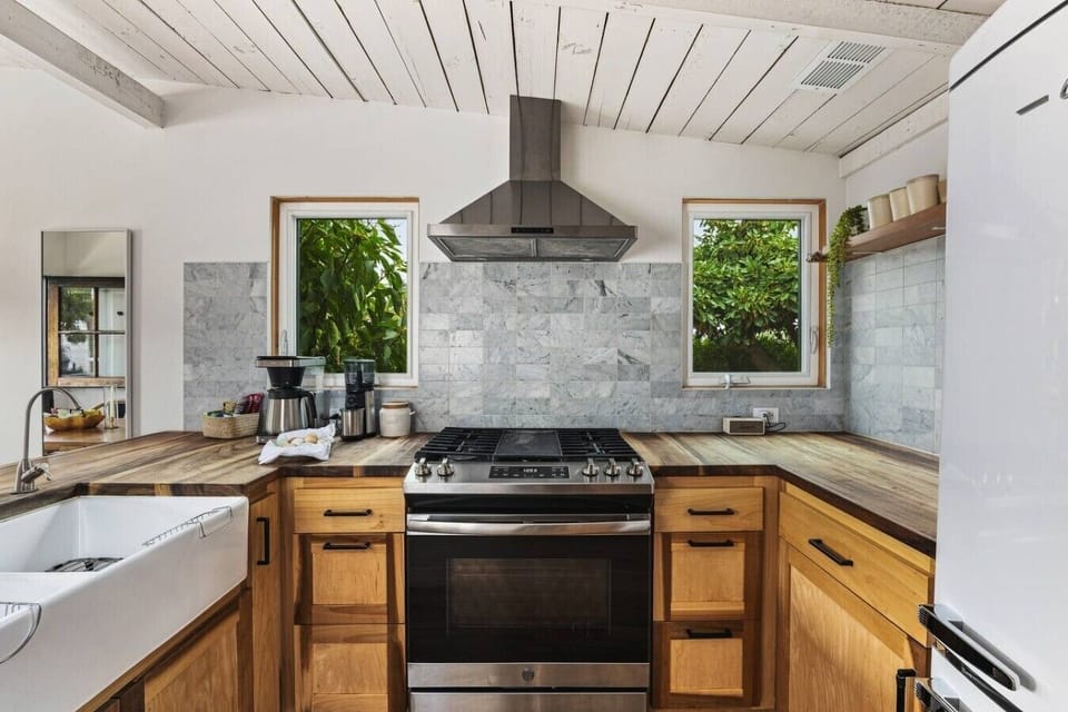 The gas stove, set between two windows that look into the greenery.