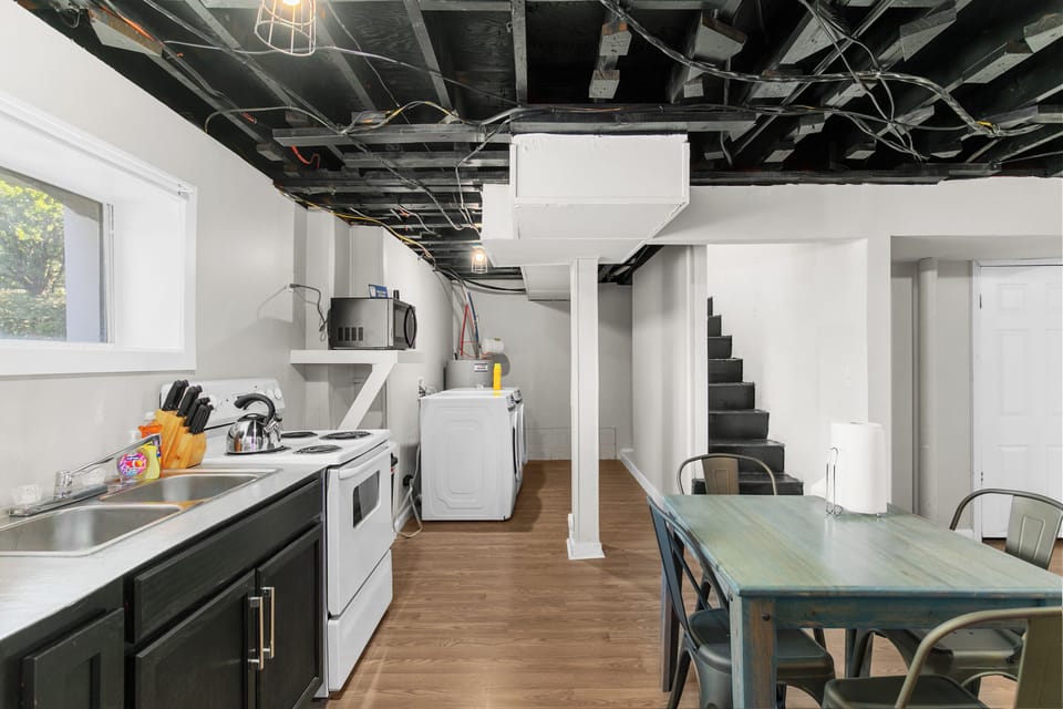 The heart of the home—this wide view shows it all: kitchen, breakfast table, laundry, and the staircase leading up to The Upper Bungalow.