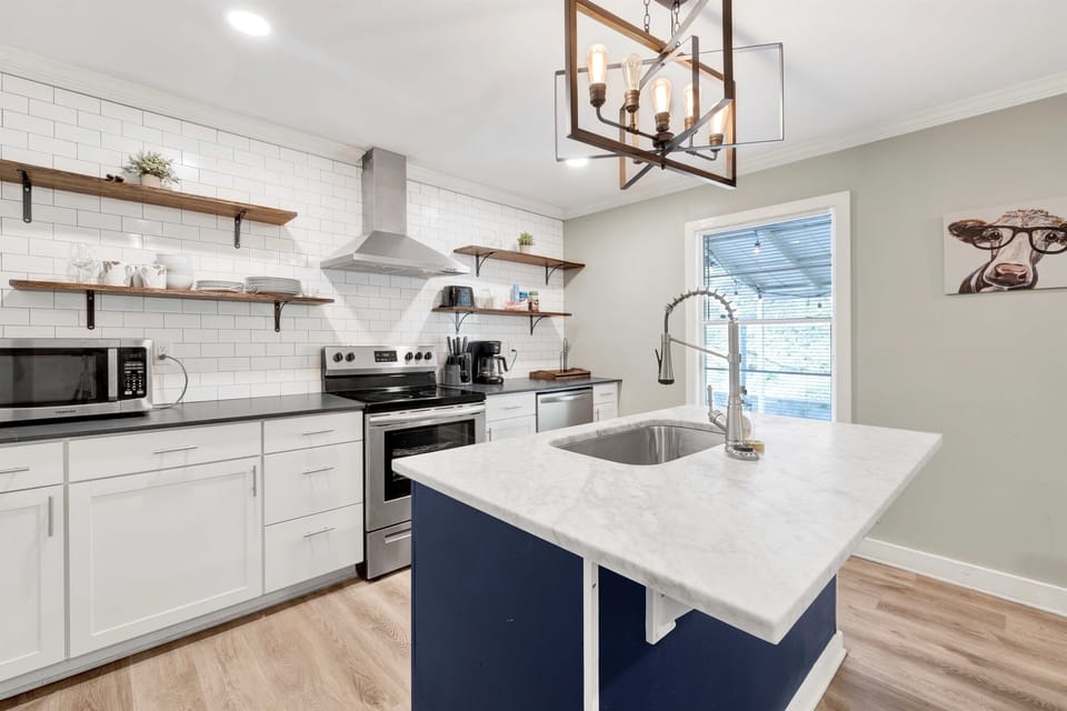 Take in the full kitchen, where marble countertops, a spacious island, and stainless appliances create a clean, functional space for cooking and gathering.
