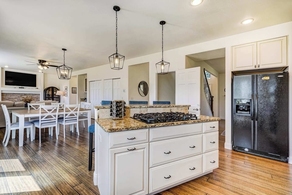 The kitchen island anchors the space with granite countertops and pendant lighting overhead, with professional-grade appliances and white cabinetry that keep the look clean and the function serious.
