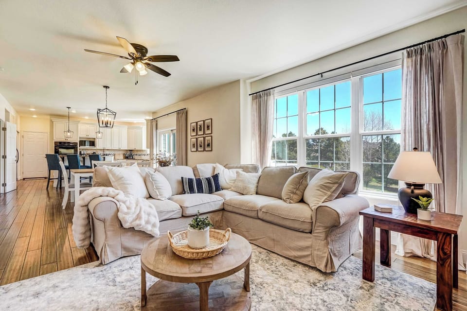 The main-level living area opens to the kitchen and dining space, with plush seating, hardwood-style flooring, and large windows that pour in Colorado light and offer views of the surrounding landscape.