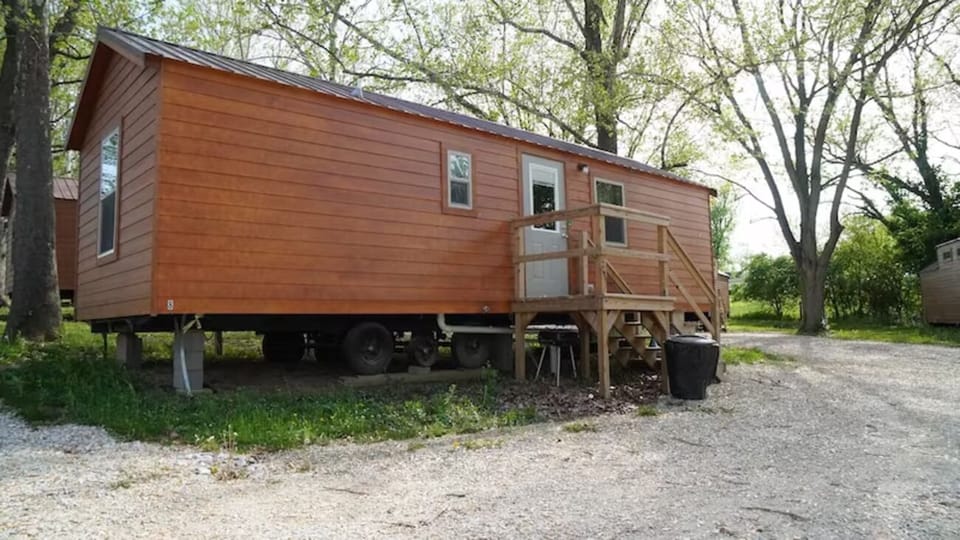 Arrive to a private cabin exterior surrounded by peaceful trees.