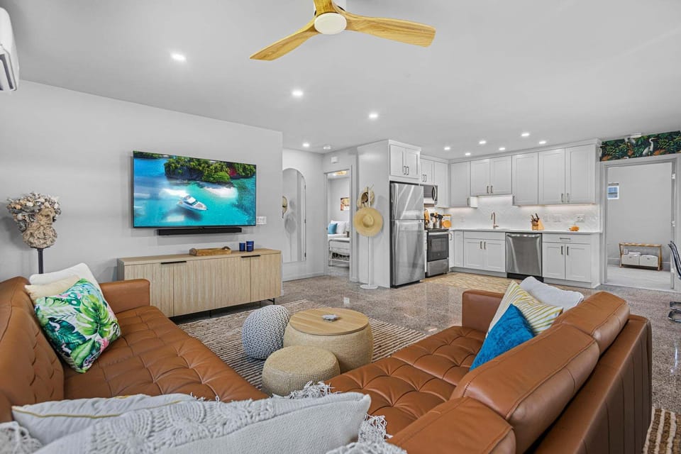 Bright & airy living room with brown leather couches and smart TV