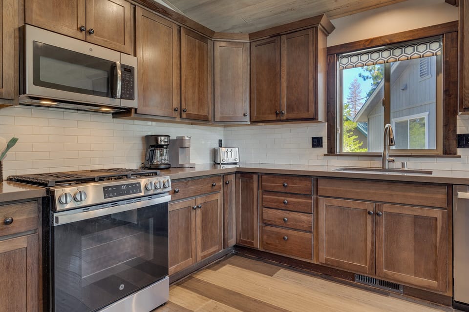 Warm wood kitchen w/ modern appliances, generous counter space & peaceful forest views