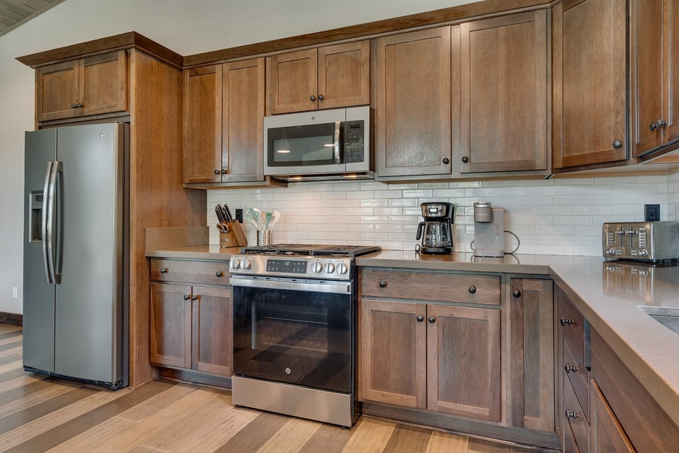 Rustic kitchen w/ stainless appliances, warm cabinetry & plenty of space for cooking together