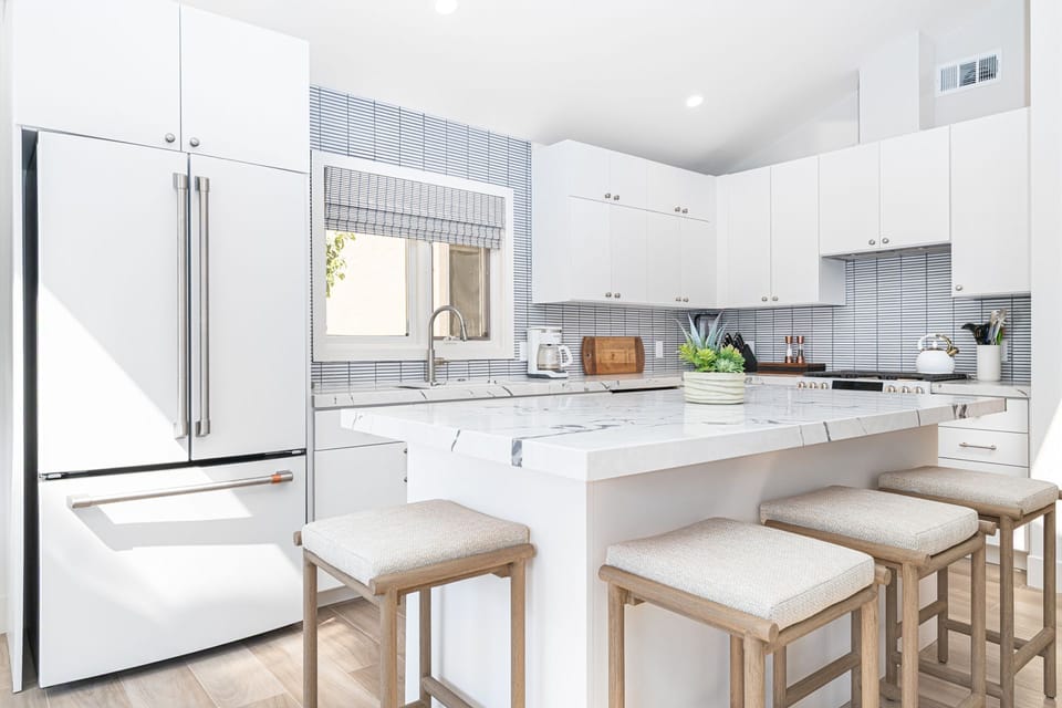 Bright, fully remodeled kitchen with custom cabinetry and barstool seating for casual dining.
                