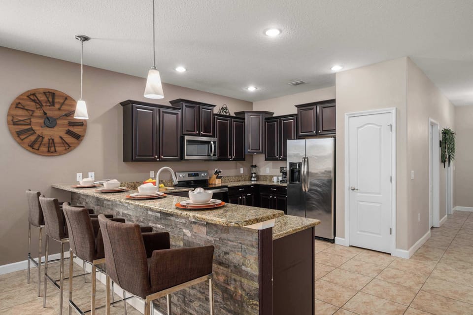 Spacious kitchen w/ dark cabinetry, island seating & room to gather while cooking