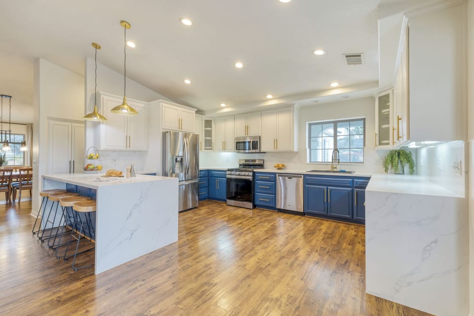 Bright, modern kitchen with bold blue cabinetry, gold accents, and a spacious island for gathering. (Main House)