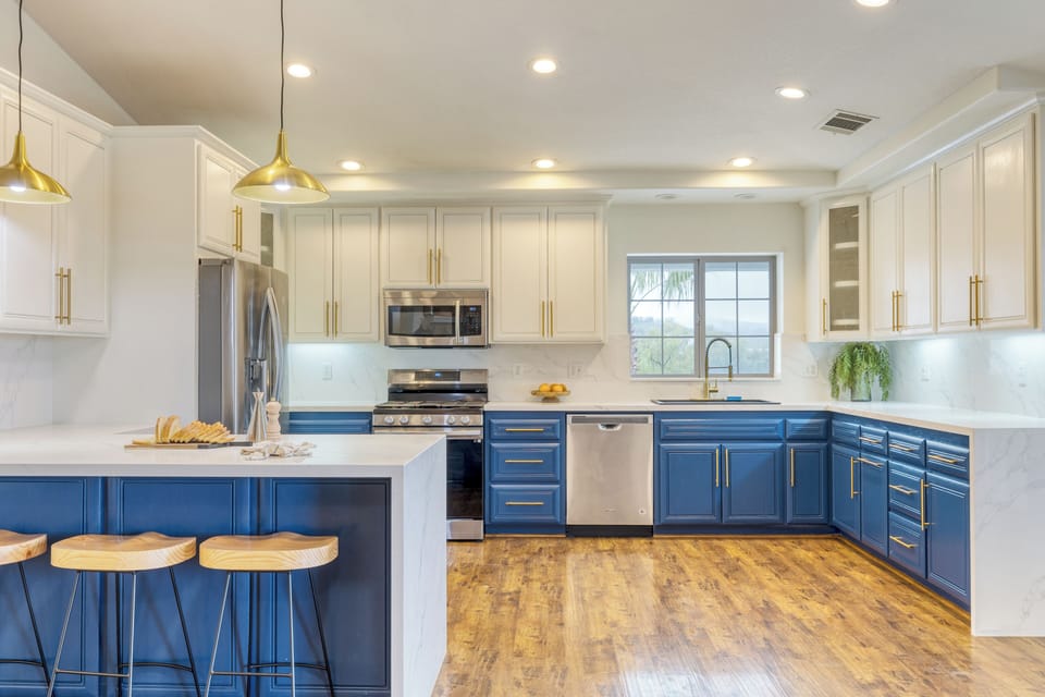 Bright, modern kitchen with bold blue cabinetry, gold accents, and a spacious island for gathering. (Main House)