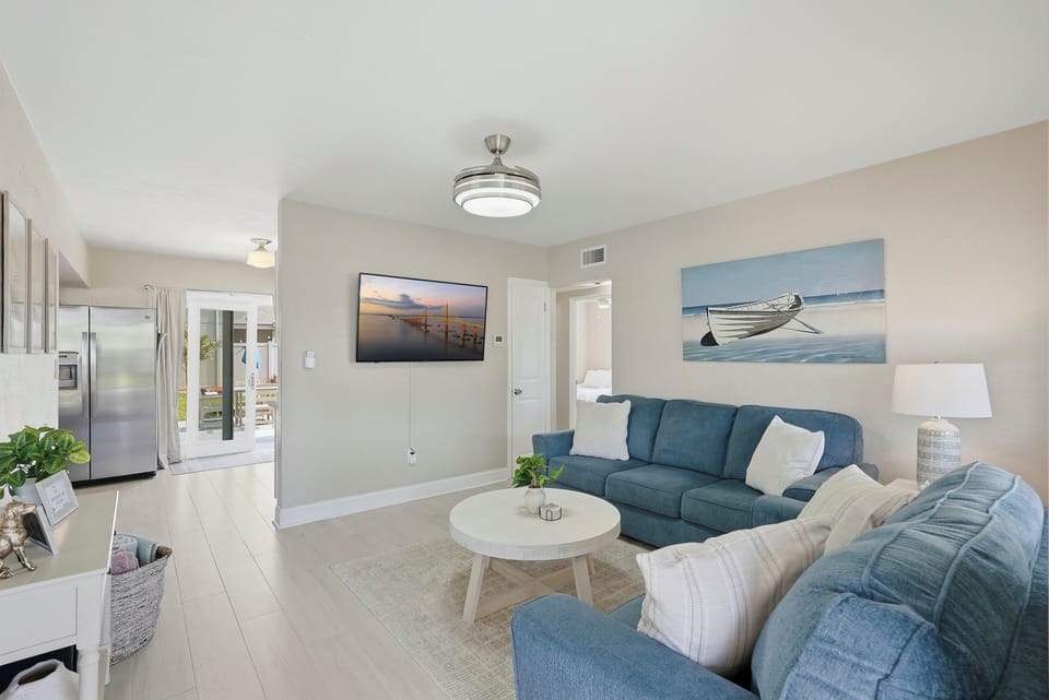 Unwind in this airy, light-filled living room featuring comfortable sofas and natural light, perfect for relaxing, gathering, and enjoying laid-back coastal comfort.