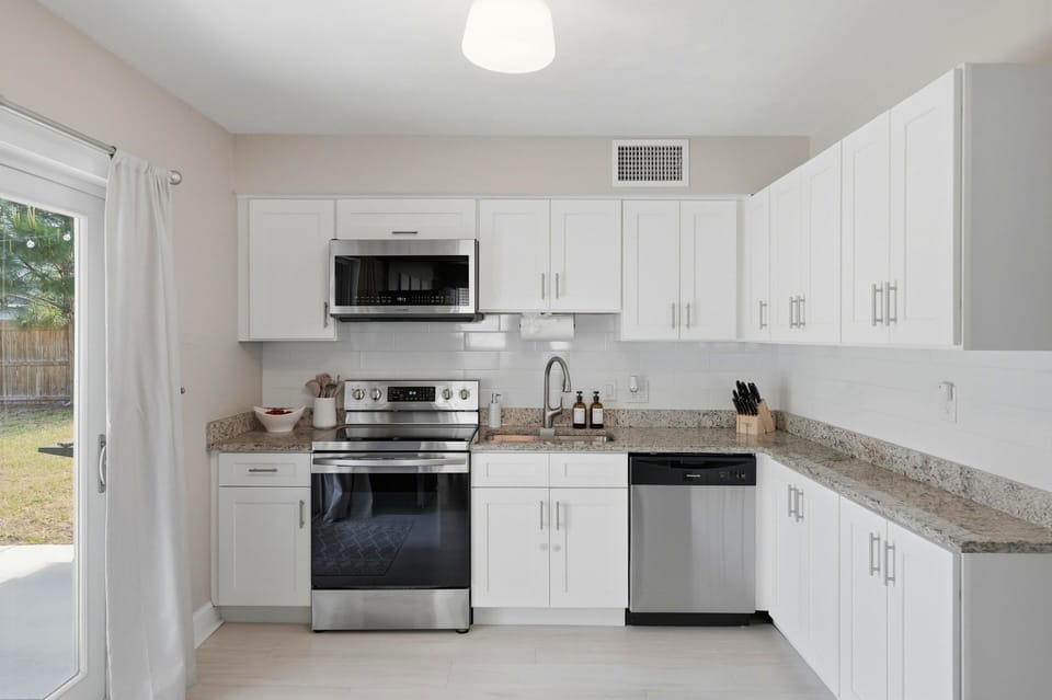 Modern and fully equipped! The kitchen boasts sleek stainless steel appliances and ample cupboards stocked with all the dinnerware you need for effortless cooking and dining, ideals for making home-cooked meals or post-beach snacks.