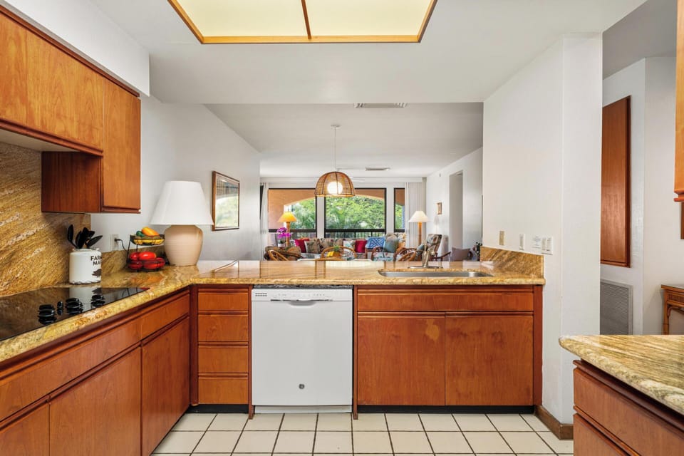 Cook your favorite meals in this well-equipped kitchen featuring warm wood cabinets, granite countertops, and modern appliances with garden views.
