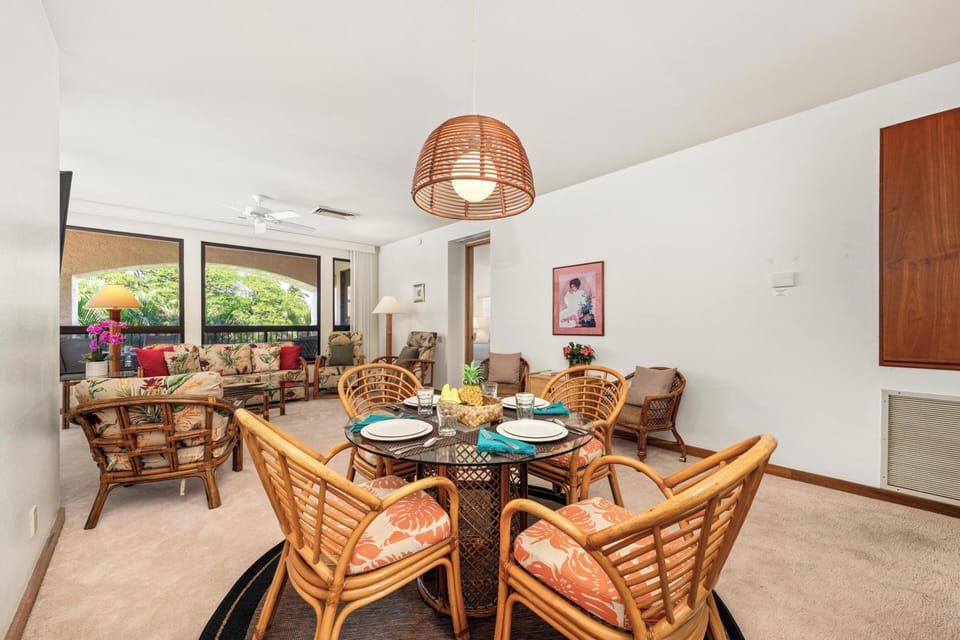 Your tropical dining space features rattan chairs around a glass table, perfect for sharing meals while enjoying garden views through floor-to-ceiling windows.