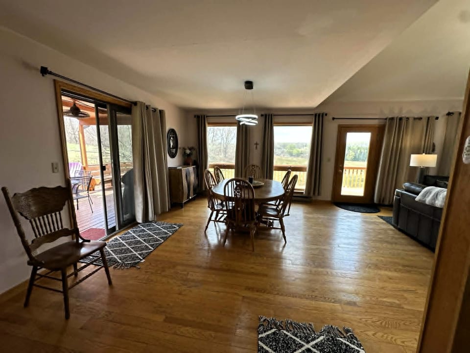 Your spacious open-concept living and dining area features warm hardwood floors and panoramic windows showcasing peaceful countryside views.