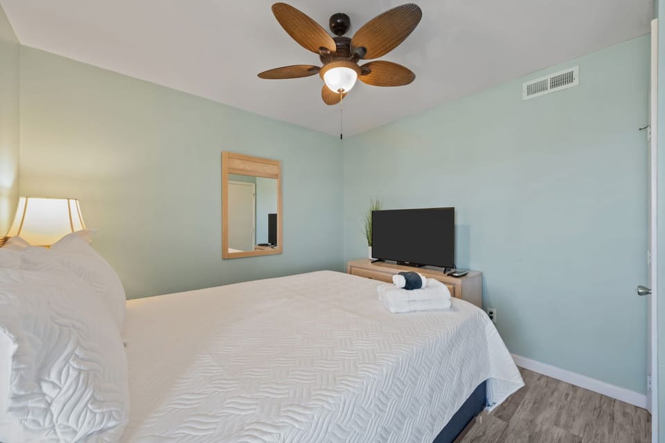 Bright coastal bedroom with queen bed and soft natural lighting